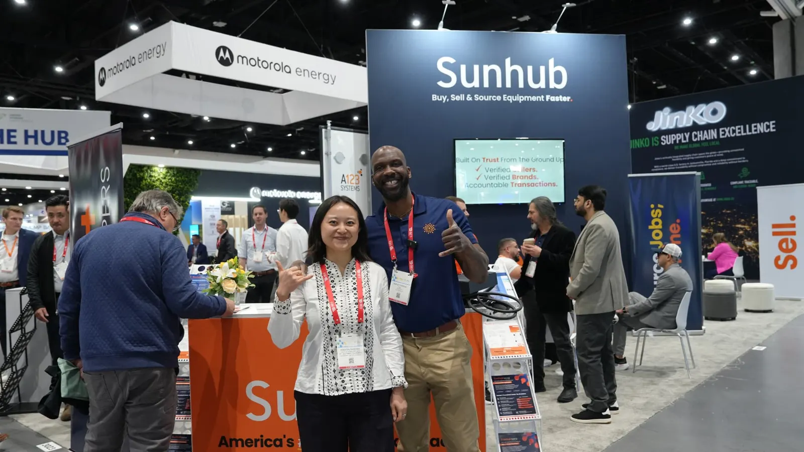 Sunhub team member with a visitor in front of the Sunhub booth wall